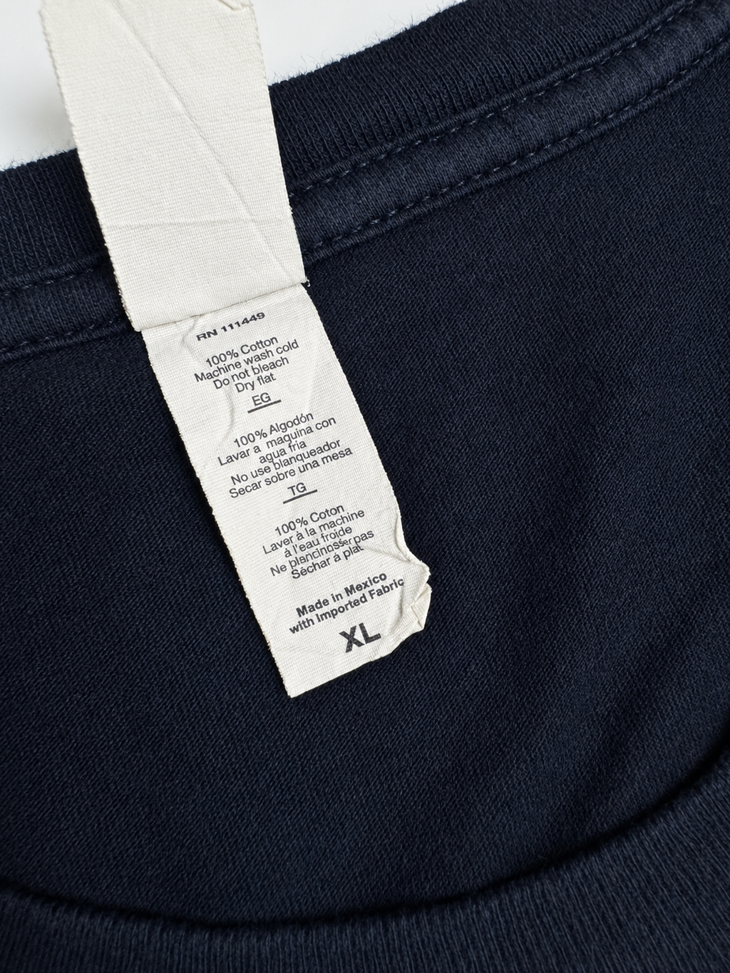 Care label showing 100 percent cotton fabric, washing instructions and XL size for the Muse T-shirt