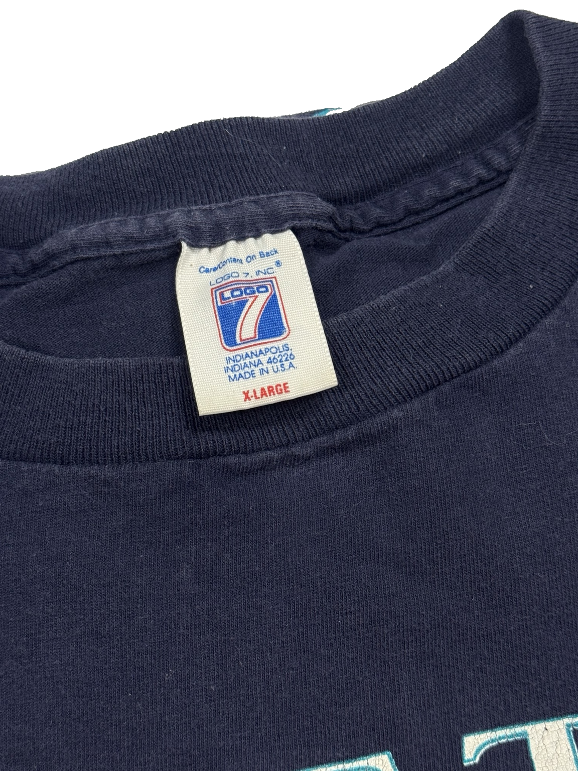 Close-up view of teal-and-white Seattle Mariners graphic on navy Logo 7 T-shirt made in USA