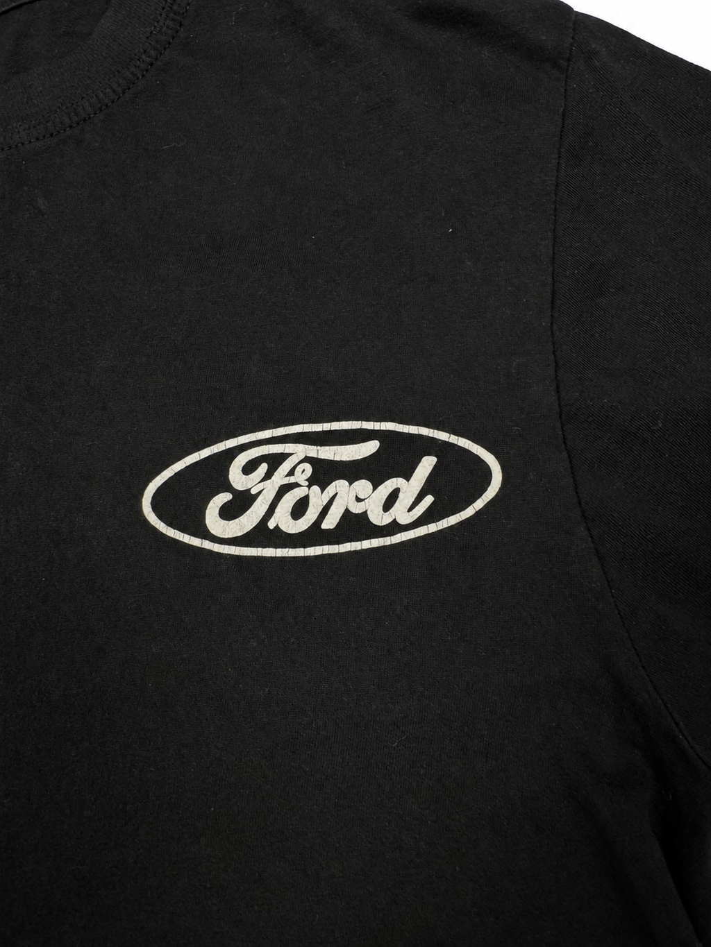 Close-up view of cracked white Ford chest logo on black T-shirt